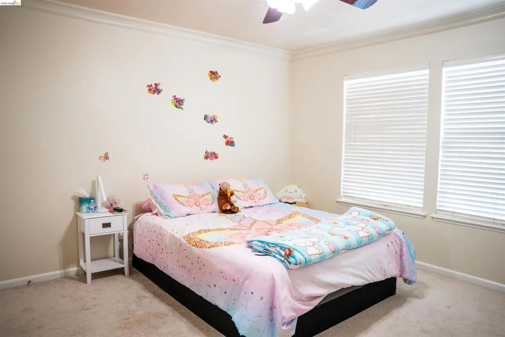 Bedroom with light carpet, crown molding, and ceiling fan