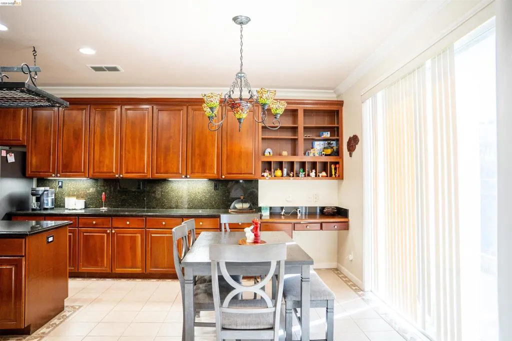 Kitchen with open shelves, decorative backsplash, crown molding, decorative light fixtures, and light tile patterned floors