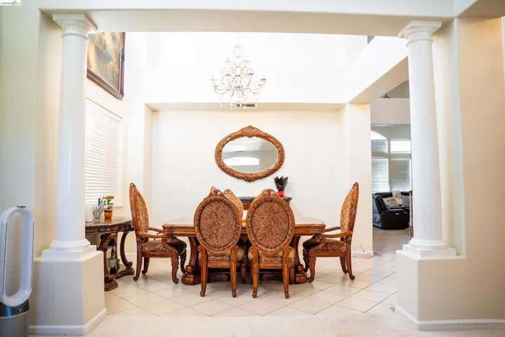 Dining room featuring ornate columns, a chandelier, and light tile patterned floors