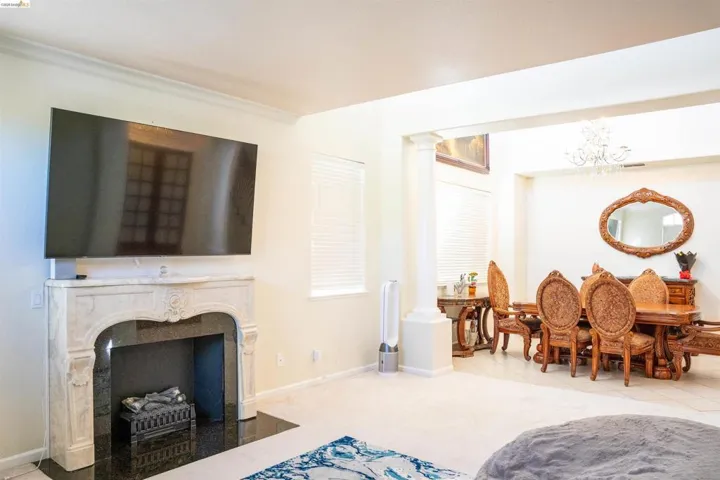 Living area featuring decorative columns, a fireplace, hanging lights, light colored carpet, and light tile patterned floors