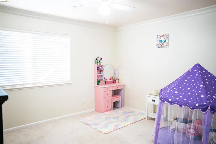 Bedroom featuring light colored carpet, crown molding, and a ceiling fan