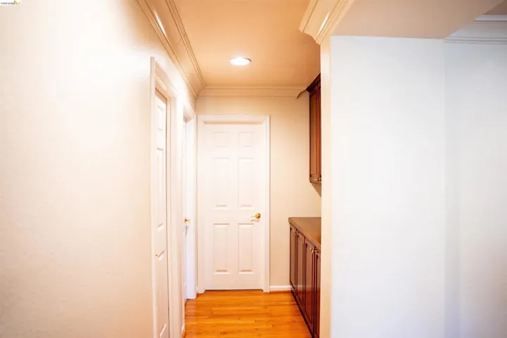 Hallway with ornamental molding, light wood-style flooring, and recessed lighting