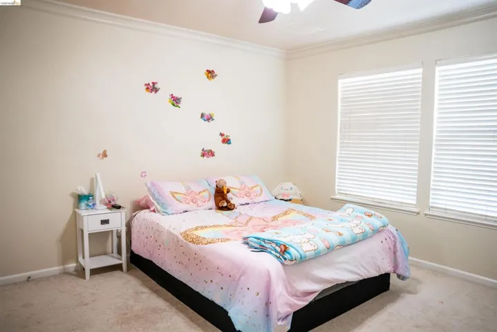 Bedroom with light carpet, crown molding, and ceiling fan