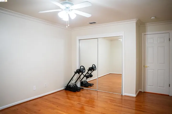 Unfurnished bedroom featuring ornamental molding, light wood-style floors, a ceiling fan, and a closet