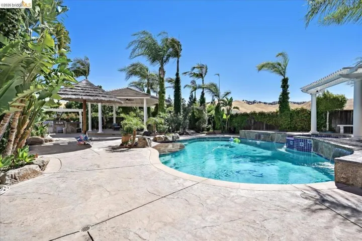 Integrated pool / hot tub featuring a patio, a fenced backyard, and a gazebo