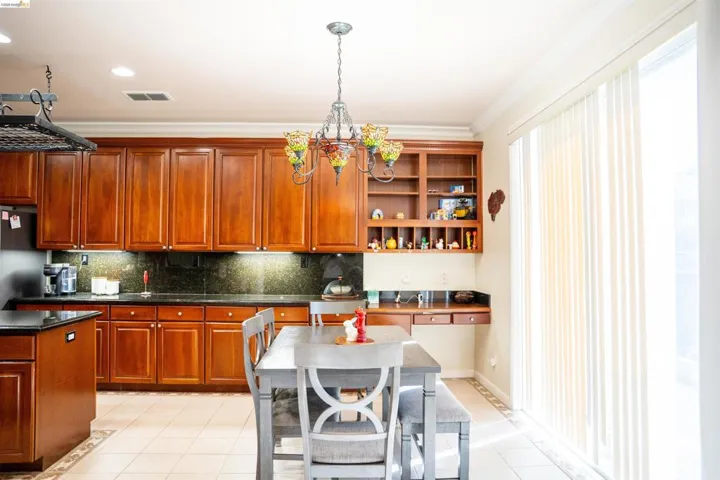 Kitchen with open shelves, decorative backsplash, crown molding, decorative light fixtures, and light tile patterned floors