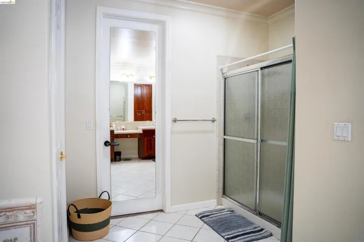 Full bath with a stall shower, light tile patterned flooring, vanity, and crown molding