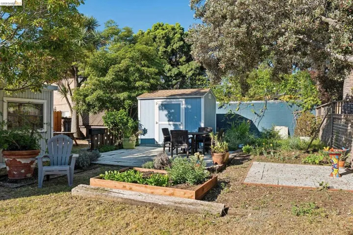 Back of property featuring a patio area, a shed, a fenced backyard, and a vegetable garden