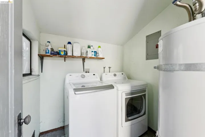 Laundry room with lofted ceiling, water heater, electric panel, and separate washer and dryer