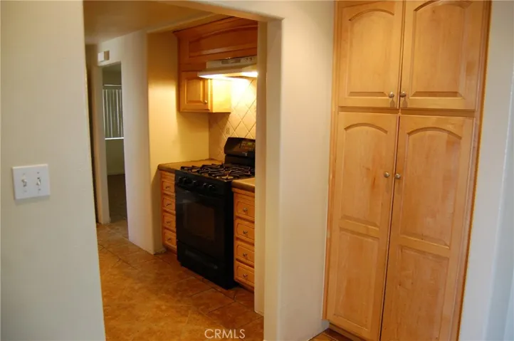 Well-appointed kitchen with natural wood cabinetry, gas range, and custom tile flooring—offering both style and practicality.