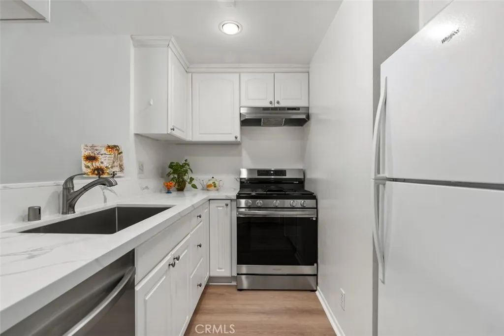 Newly remodeled kitchen features new quartz counters with breakfast bar, new farmer's sink with new faucet and garbage disposal, all lnew appliances including dishwasher, stove and refrigerator.