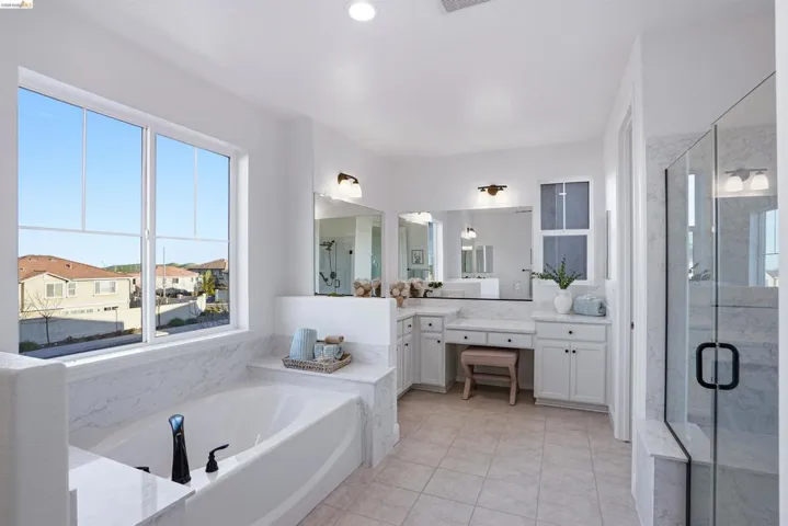 Full bathroom featuring vanity, a marble finish shower, a garden tub, and light tile patterned floors
