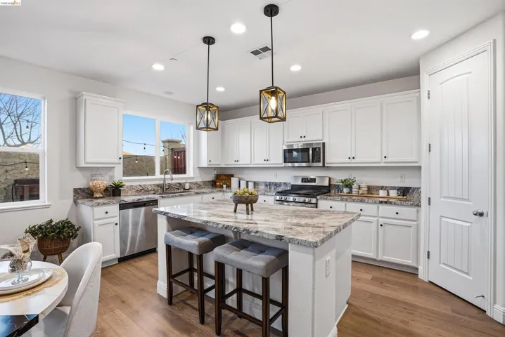 Kitchen with stainless steel appliances, a breakfast bar, a kitchen island, and white cabinets