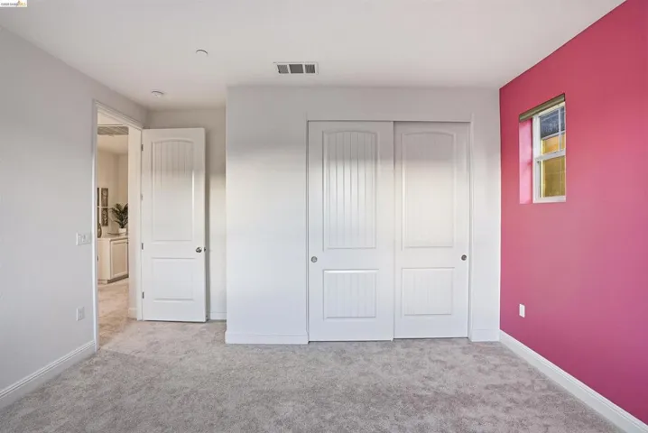 Unfurnished bedroom with light carpet and a closet