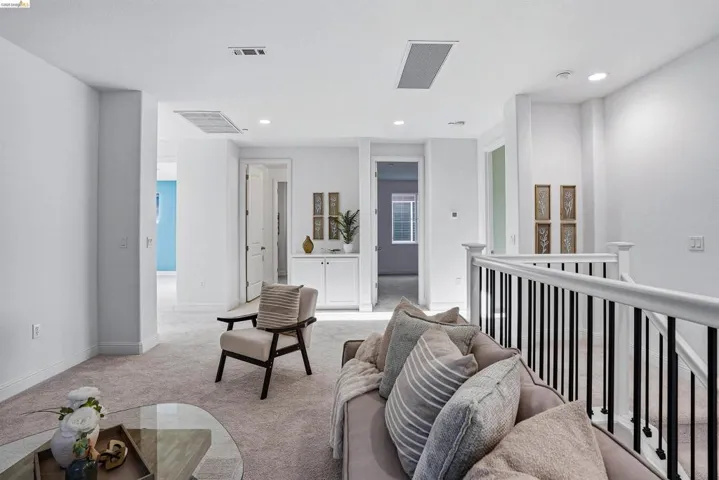 Living area with light carpet and recessed lighting