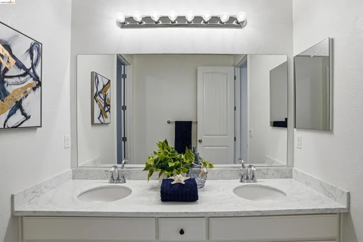 Bathroom with a textured wall and double vanity