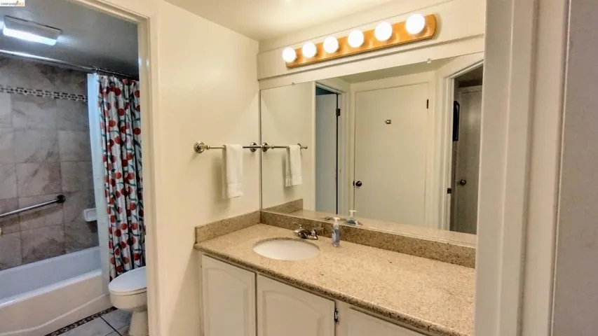 Full bath featuring vanity, light tile patterned flooring, and shower / tub combo