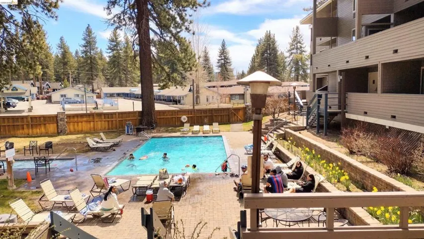 Community pool with a patio area, a fenced backyard, and a residential view