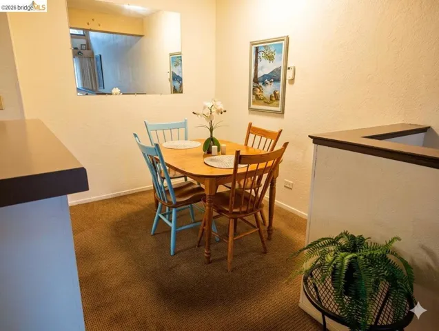 Dining area with a textured wall and dark​​‌​​​​‌​​‌‌​​‌​​​‌‌​​​‌​​‌‌​​‌‌​​‌‌​​​​ carpet