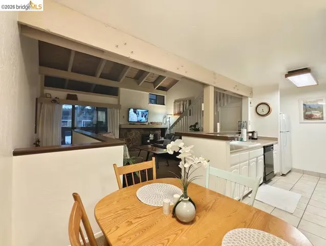 Dining area featuring light tile patterned floors and vaulted ceiling with beams