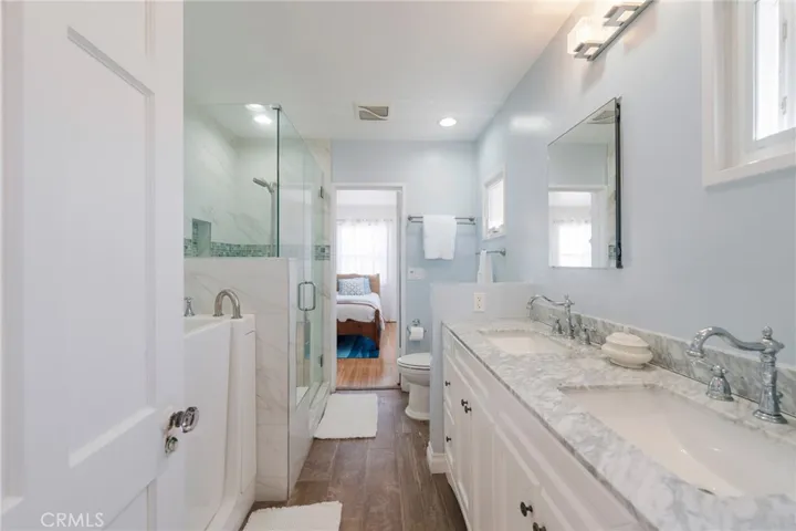 Beautiful coastal bathroom with an easy-entry soaking tub, separate glass shower, and dual vanities. Jack-and-Jill layout connects the ocean-view primary bedroom and courtyard-view bedroom—perfect for a seamless, relaxing beach getaway.