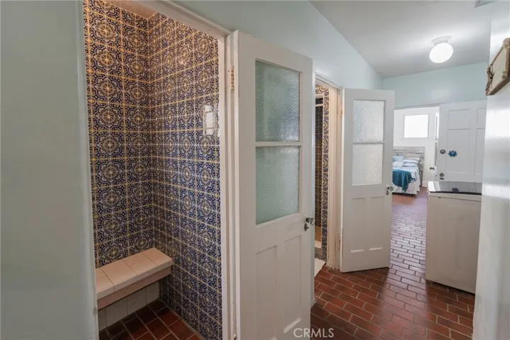 Private hallway off the kitchen featuring two showers with imported Spanish tile, a 1/4 bath, laundry, and access to the third bedroom—ideal for guests, teens, or a nanny suite.