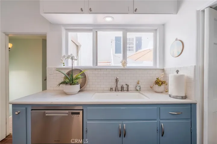 Bright kitchen with farmhouse sink, subway tile backsplash, and garden window—filled with natural light and coastal charm.