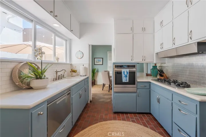 Bright, coastal kitchen with abundant cabinetry, stainless appliances, and natural light—functional layout with charming vintage character.