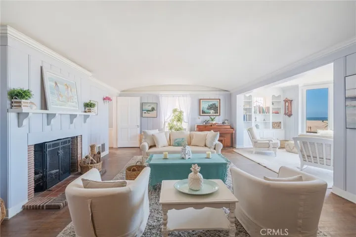 Charming coastal living room with fireplace, built-ins, and ocean-view sitting area. Bright, open layout with soft tones and inviting spaces for relaxing or entertaining.