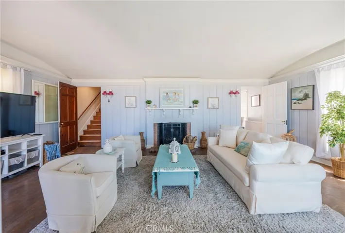 Inviting living room with fireplace centerpiece, soft coastal tones, and abundant natural light. Comfortable seating and open flow create a warm, welcoming space.