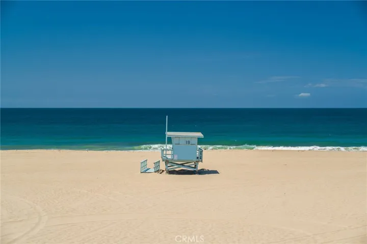 Direct oceanfront view from the primary bedroom, featuring the beach and iconic lifeguard tower.