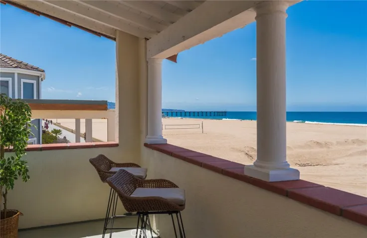 Covered oceanfront balcony off the primary bedroom with stunning beach and pier views. A peaceful spot to unwind and take in the coastline.