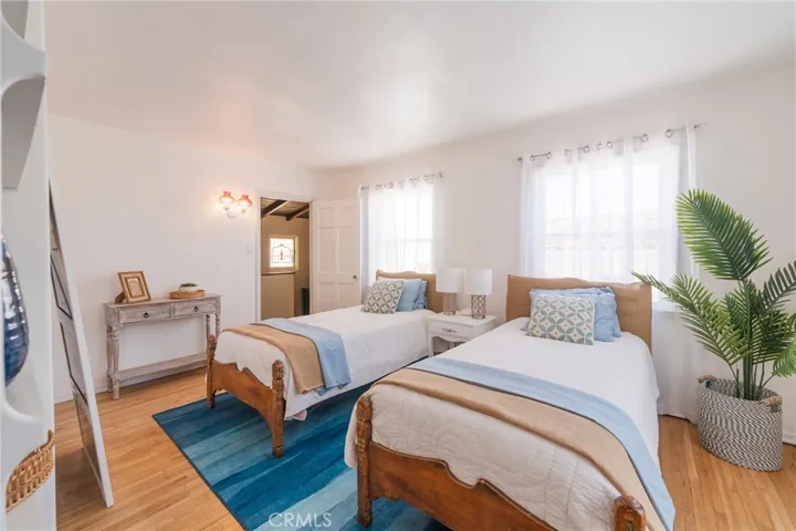 Bright, breezy bedroom with two twin beds (can be converted to a king), overlooking the courtyard with morning sunshine—perfect for a relaxing beach getaway.