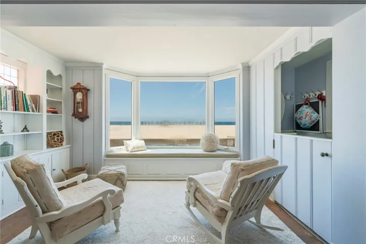 Cozy ocean-view sunroom with built-in seating and custom shelving—ideal for relaxing by the beach. Window currently being replaced.