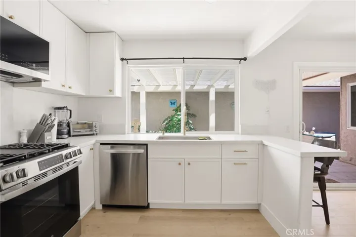 Beautiful and Large White Kitchen with Large Window Facing Back Patio