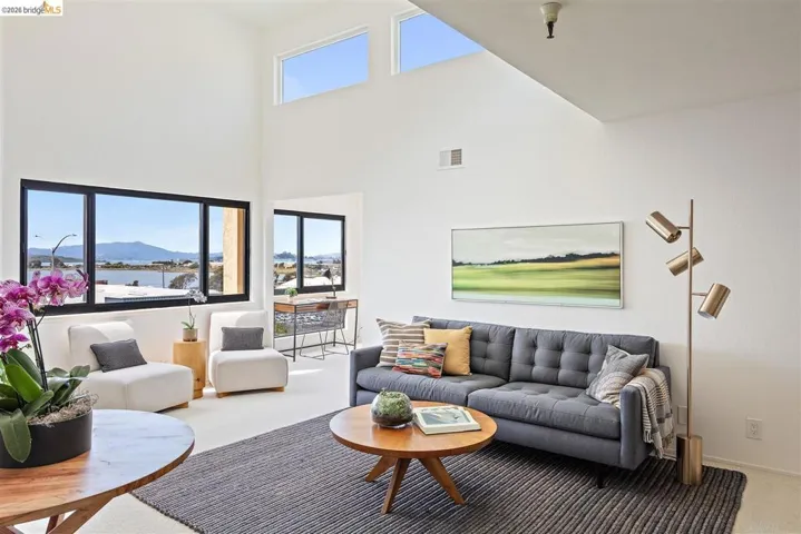 Carpeted living room featuring healthy amount of natural light, a mountain view, and a high ceiling