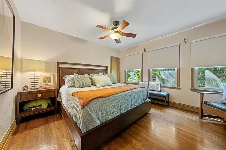 One of four bedrooms downstairs with ceiling fan, wood flooring, closet in the corner and the windows face the side yard.
