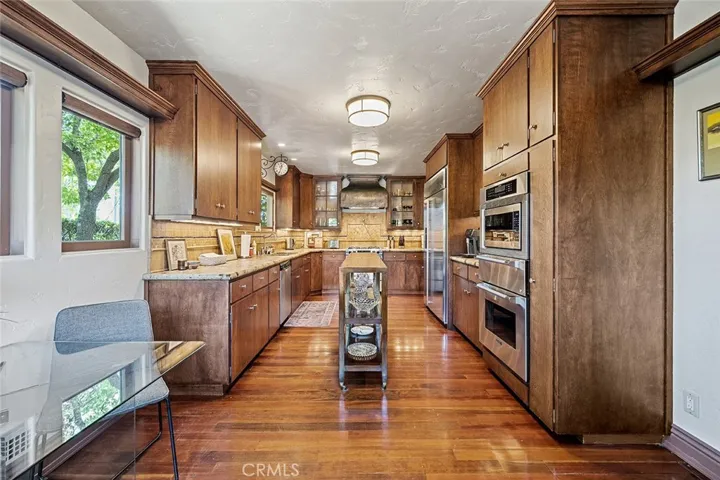 Beautiful galley kitchen standing from the exterior door to the backyard. Breakfast nook to the left. Wooden rolling table in the middle remains with the home and is a perfect place to have decor, cookbooks, pretty bowls or you decide.