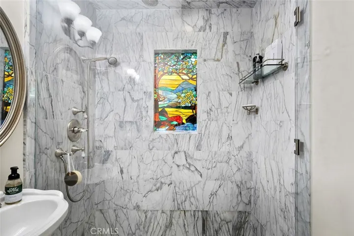 Lower level 3/4 bathroom with a stained glass window adding character to this space located near the lower level two bedrooms.