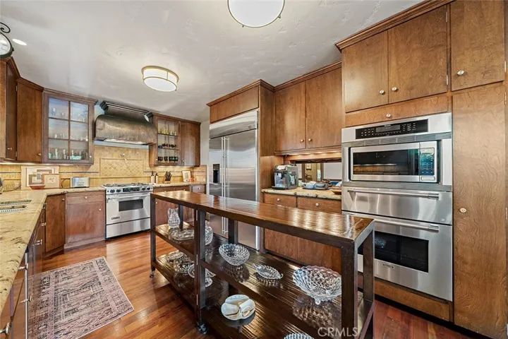 Beautiful with warm tones galley kitchen with stainless steel oven, microwave, refrigerator, dishwasher, gas stove and wooden rolling table in the middle to remain. Pass through to the dining situated between the oven and refrigerator.