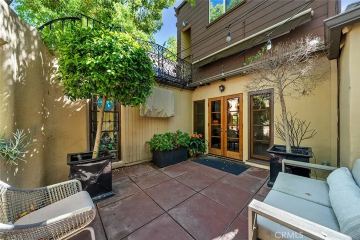 Stained glass window helps set the charm of the outdoor living area. Covered in the image is an outdoor television to remain. French doors to the dining room.
