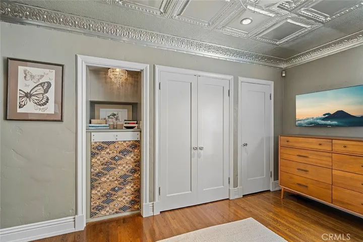 The primary bedroom has a walk in closet located in the en suite as well as the closets behind the doors and space to store more in the built in shelves. Notice the metal ceiling from Tennessee that adds to the charm and whimsical feeling of this home.