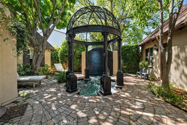 Gazebo accenting a large hot tub set between the gym and the home. Large waterfall wall at the end of the hot tub.