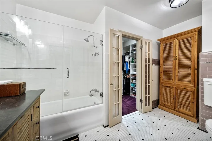 Primary en suite with walk in closet. The enclosed shelving unit remains and is a perfect place for linens and toiletries.
