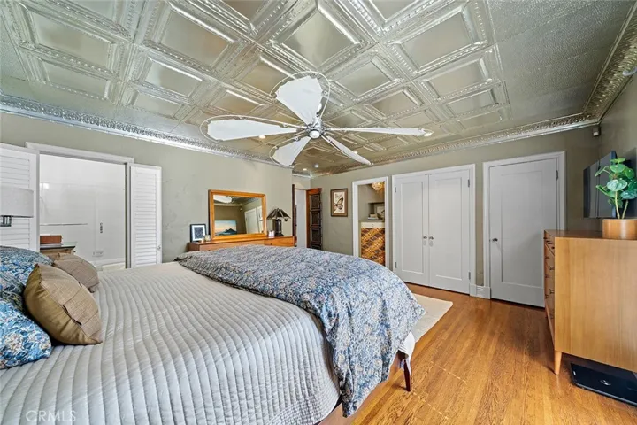 The primary bedroom has a walk in closet located in the en suite as well as the closets behind the doors and space to store more in the built in shelves. Notice the metal ceiling from Tennessee that adds to the whimsy charm of this home.