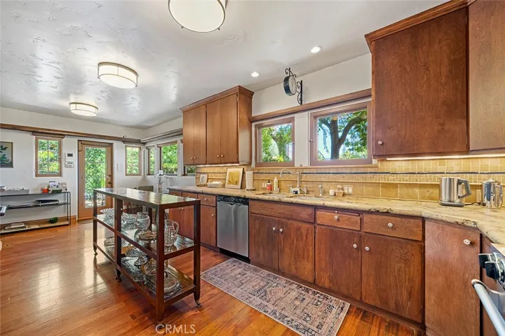 Plenty of space to work in the wide galley kitchen with granite counters. Stainless steel appliances remain along with the wooden rolling table. Window view above the sink faces the side yard towards Martelo with privacy hedges.