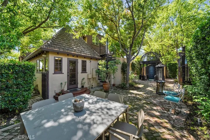 Plenty of shade from the lush trees and whimsy charm of brick pavers and the beauty of the home.