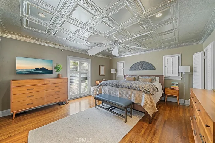 Spacious primary bedroom with wood flooring, metal ceiling from Tennessee that adds to the whimsy charm of this home.