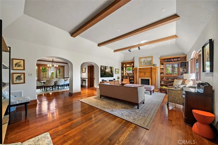 Standing from the entry area and primary ensuite overlooking the ever so grand living room offering comfort, elegance and style with high beamed ceilings, archways to the formal dining and lighting that is perfectly situated to accent any artwork one may have. The fireplace mantle from Normandy beckons to be sit in front of while framed by built in shelves and speakers.