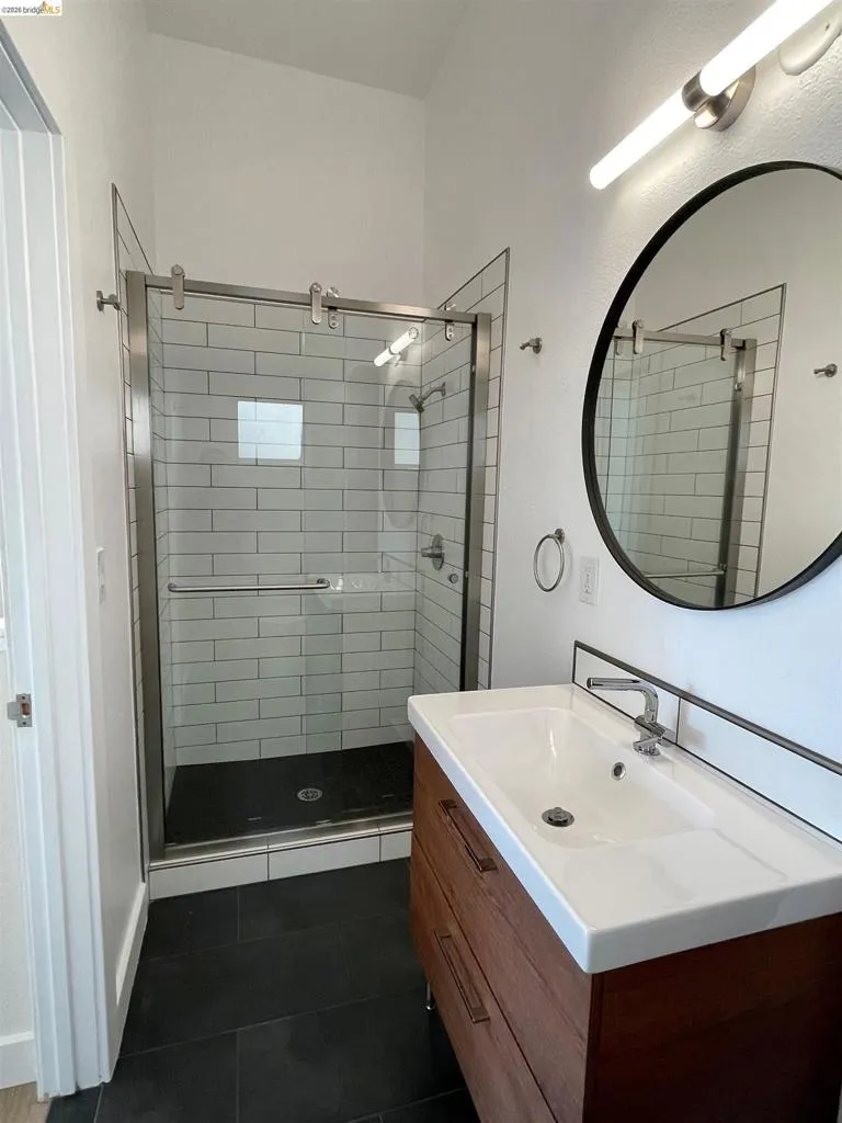 Bathroom featuring vanity, dark tile patterned flooring, and a stall shower
